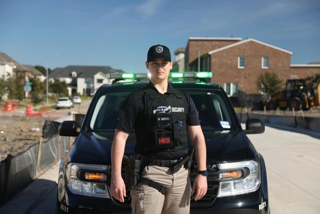 Security officer standing in front of a patrol vehicle in a suburban neighborhood, League City, Texas.